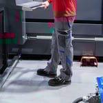 Mitarbeiter steht mit Sicherheitsschuhen auf rutschhemmender Arbeitsplatzmatte an einer Maschine zur Reduzierung von Stolper- und Rutschunfällen.