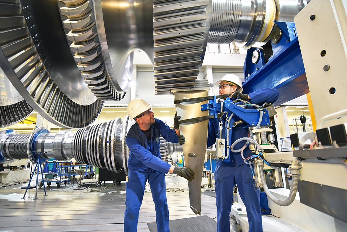 Männer in der industriellen Produktion: die ergonomische Gestaltung von Arbeitsplätzen beinhaltet auch rückenschonende Arbeitsweisen durch Maschinen. 