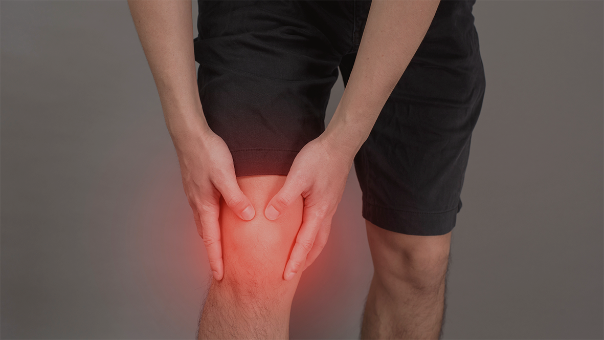 Mann mit Schmerzen im Kniegelenk: Dies deutet oft auf eine falsche Sitzhaltung oder Bewegungsmangel hin. 