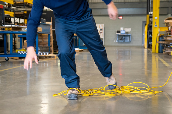 Ein Arbeiter stolpert über ein am Boden liegendes Kabel: Die Betriebssicherheit erfordert allerdings aufgeräumte Gänge. 